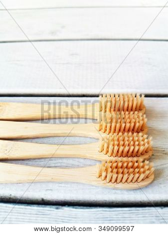 A Family Set Of Four Wooden Toothbrushes On White Wooden Background With Copy Space