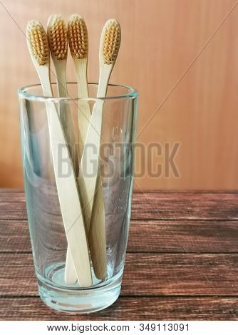 A Family Set Of Four Wooden Toothbrushes In A Glass On Wooden Background With Copy Space