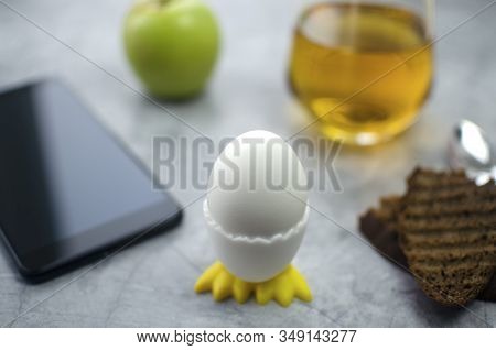 Breakfast On A Concrete Background A Glass Of Apple Juice, An Egg In A Stand With Knives, Chicken, B