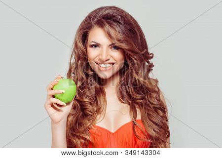 One Apple A Day Keeps Doctor Away. Curly Brunette Woman Smiling Holding Green Apple Toothy Smile Iso