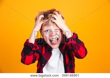 Little Boy Screamin With Opened Mouth. Wearing Red Checkered Shirt On Yellow Background
