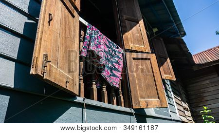 Batik Fabric Hanging On The Window Of Rumah Kampung Under The Bright Sunlight.