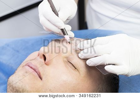 Young Man Microblading Procedure To Improve The Condition Of A Mans Eyebrows In A Beauty Salon.