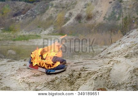 Burning Sports Sneakers Or Gym Shoes On Fire Stand On Sandy Beach Coast. Athlete Burned Out. Physica