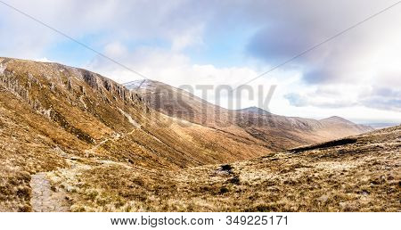Footpath Leading To Snow Capped Peak Of Slieve Donard Mountain. Mourn Wall Surrounding Mourn Mountai