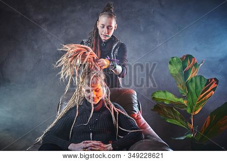 In A Misty Room Full Of Smoke Dread Master Is Making A Dreadlocks For Blond Girl.