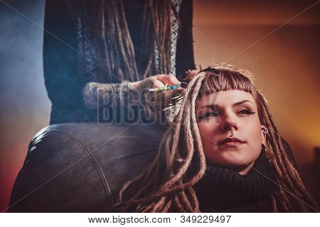 Talented Dreadlock Master Is Working On Dreads For Pretty Blond Girl In The Dark Room.