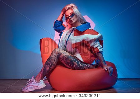 Avantgarde Portrait Of Young Woman With Tattoo On Her Leg, She Is Sitting On Bean Bag.