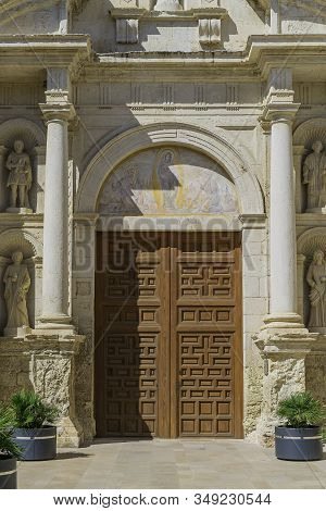 Medieval Stone Cathedral With Wooden Door. Entrance Of The Main Church, Iglesia Arbos In The Village