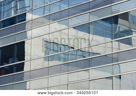 Reflective Building In Which The Surrounding Ones Are Reflected. Image Of Parallel And Perpendicular