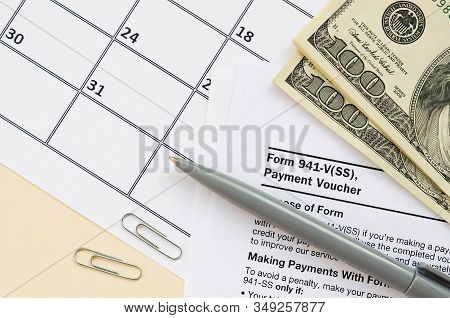 Irs Form 941-v Payment Voucher Blank Lies With Pen And Many Hundred Dollar Bills On Calendar Page