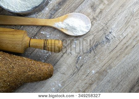 A Loaf Of Bread Along With Rocking For The Dough In A Craft Bag Stand On A Wooden Table, Next To It 