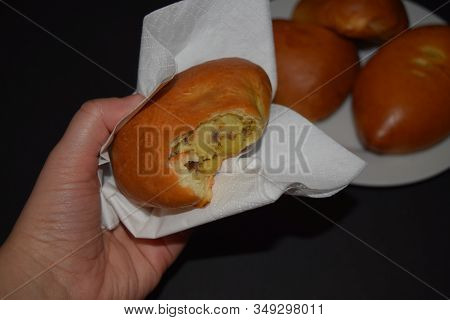Someone Is Holding A Nibbled Homemade Pie With Potatoes In A White Napkin On A Black Background. Clo