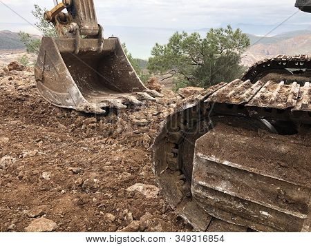 Excavator Scoop Flattens Soil During Road Construction On The Rocky Soils