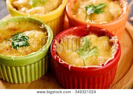Closeup Casserole With Baked Cheese, Chicken And Mushrooms In Multicolored Cocoanuts On Wooden Board