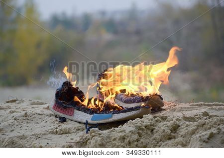 Burning Sports Sneakers Or Gym Shoes On Fire Stand On Sandy Beach Coast. Athlete Burned Out. Physica