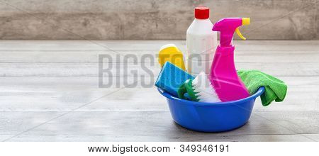 Cleaning Supplies In A Blue Bowl, Wooden Floor Background.