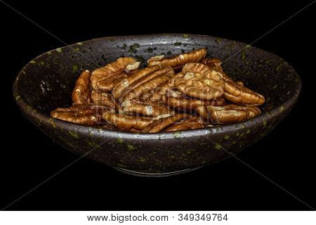 Lot Of Whole Tasty Brown Pecan Half In Glazed Bowl Isolated On Black Glass