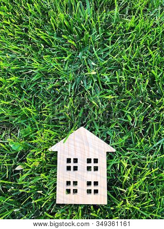 Miniature Wooden House On Green Grass. Real Estate Concept. Modern Housing. Eco-friendly And Energy 