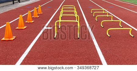 Cones And Mini Hurdles Set Up In Lanes On A Track For Speed And Agility Practice.