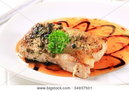 ผัดหมูสามชั้นบนจานสีขาวกับน้ำซอสราดหน้าตกแต่ง ด้วยผักชีฝรั่ง