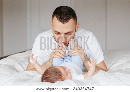 Happy Caucasian Father Holding Newborn Baby. Male Bearded Man Parent Hugging Kissing His Child Daugh