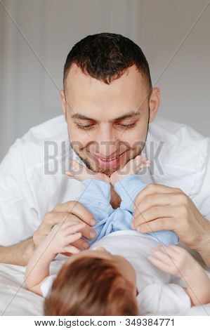 Happy Caucasian Father Holding Newborn Baby. Male Bearded Man Parent Hugging Kissing His Child Daugh