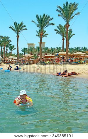 Hurghada / Egypt. 30 July 2018: Little Girl Swimming In Water Lying On Inflatable Circle During Summ
