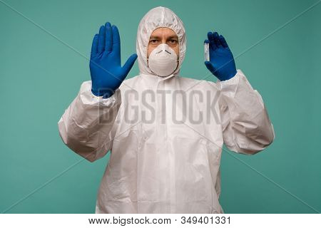 A Male Doctor In Protective Overalls And A Mask Holds An Ampoule With A Vaccine In His Hands Shows S