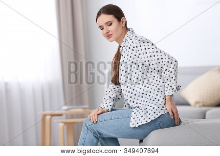 Young Woman Suffering From Hemorrhoid At Home. Space For Text