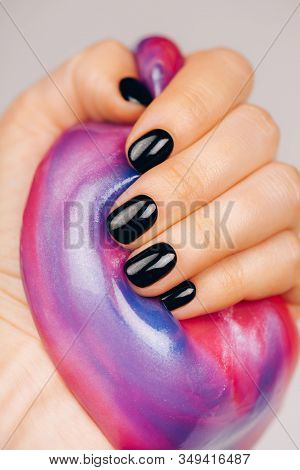 Hands With Black Manicure Holding Slime In Blue And Pink Vibrant Colors