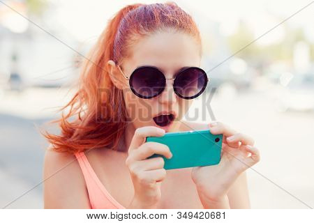 Sms. Closeup Portrait Funny Shocked Young Red Head Girl Woman Looking At Phone Seeing Surprising New