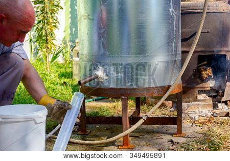 Man Takes A Sample Of Freshly Distillated Liquor, Alcohol In The Laboratory Graduated Cylinder.