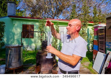 Man Is Using Glass Alcoholmeter For Determining The Amount, Concentration Of Alcohol In Liquor. Samp