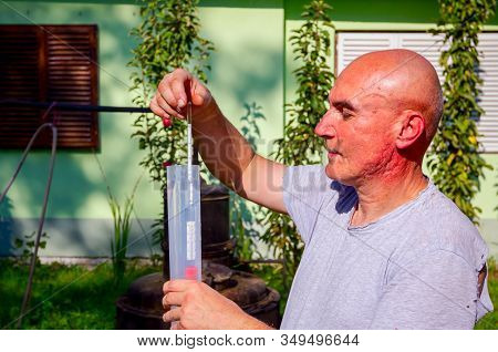 Man Is Using Glass Alcoholmeter For Determining The Amount, Concentration Of Alcohol In Liquor. Samp