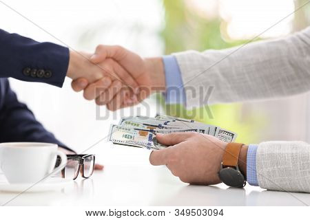 Man Shaking Hands With Woman And Offering Bribe At Table In Office