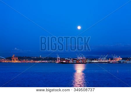Big Lune With Trail On Water Of Elliot Bay Over Seattle Port Night View, Wa, Usa