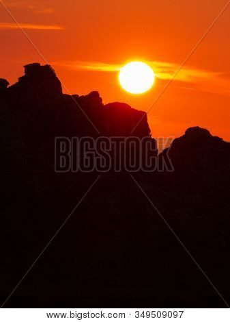 The Sun Setting Behind A Cliff Silhouette. Negative Space.