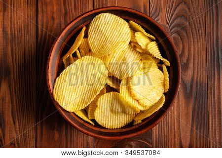 Wavy, Potato Chips In A Plate On A Wooden Table. Top View Snacks. Stock Photo Potato Chips With Empt