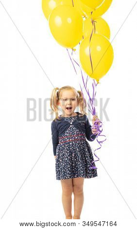 smiling 3 year old Caucasian girl with pigtails holding yellow balloons. isolated on white. concept of happiness and lightheartedness.