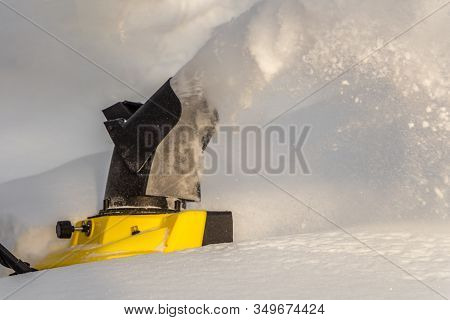 Man Is Brushing White Snow With The Yellow Electric Snow Thrower In A Winter Garden