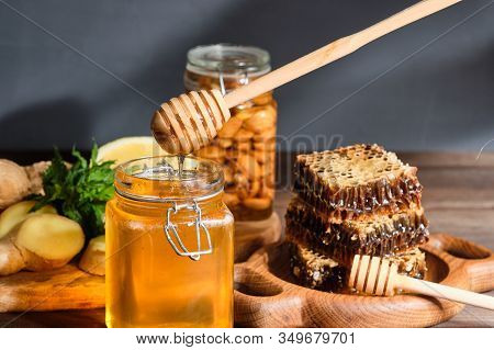 Honey In Honeycombs On A Wooden Plate And Golden Honey In A Jar With Nuts And Comb For Honey With Le