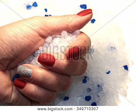Crystals In A Woman's Hand With A Red Manicure.