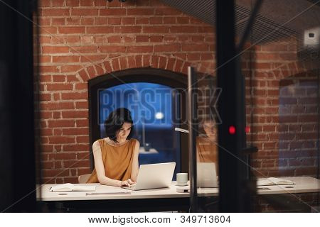 Young Businesswoman With Dark Hair Sitting At The Table And Typing On Laptop Computer She Working At