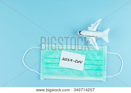Protective Face Mask And Airplane Model On Blue Background, Against Novel Coronavirus (2019-ncov) Or