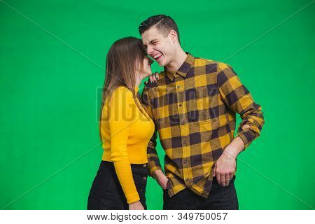 Portrait Of Girl Whispering Into Mans Ear, Telling Him Something Really Funny Because He Is Smiling 