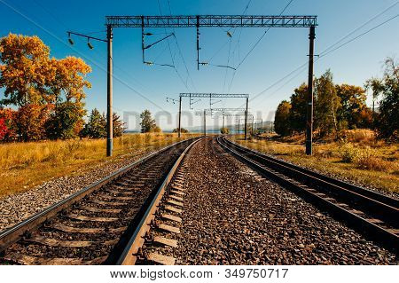 Parallel Railway Tracks And Overhead Lines Through The Forest. Autumn