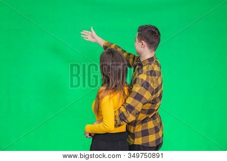 Amazed Young People Looking And Pointing Away At Something Really Increadible On Green Background.