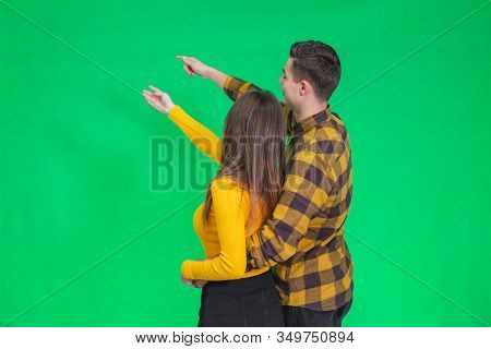 Amazed Young People Looking And Pointing Away At Something Really Increadible On Green Background.