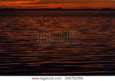 Sunset In Chascomus, The Orange Sun Is Reflected On The Surface Of The Lake. Province Of Buenos Aire